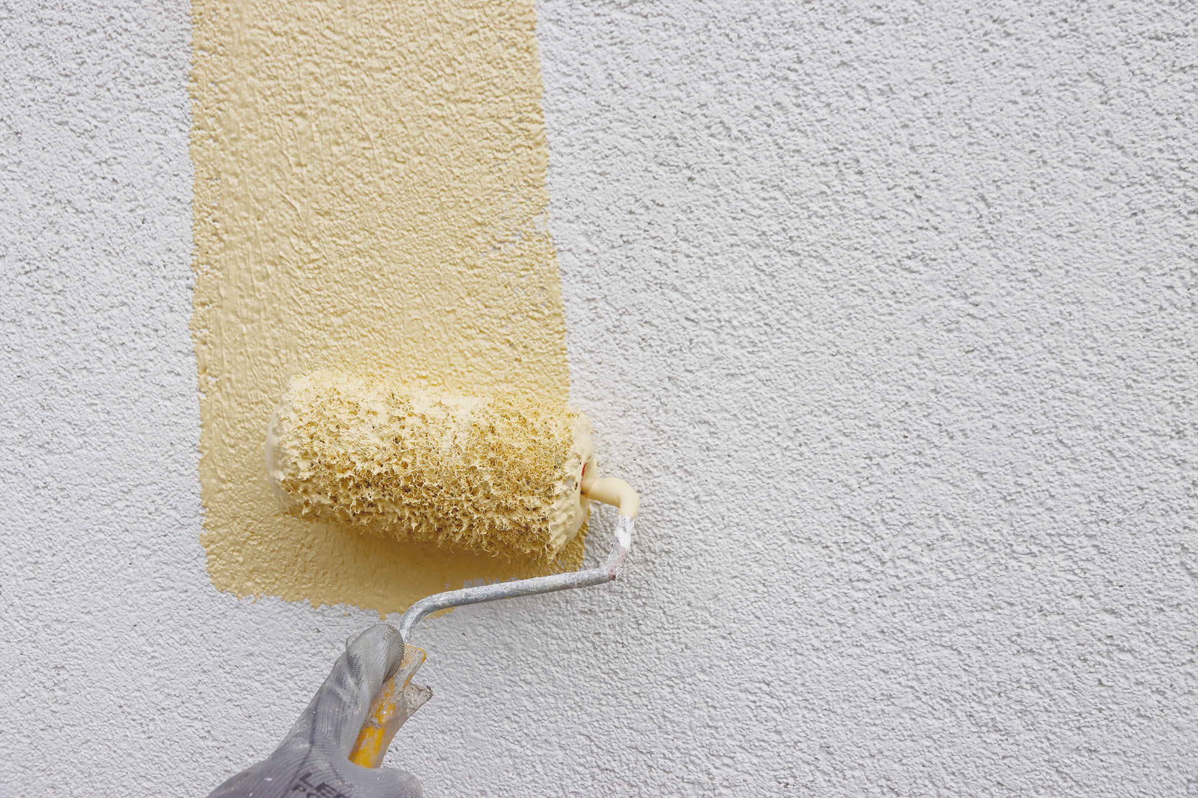 Rouleau peinture jaune claire sur façade gris clair