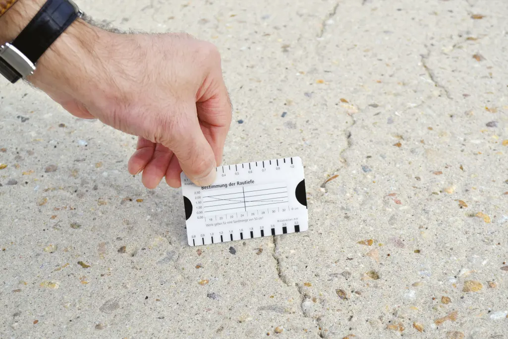 Main tenant un fissuromètre qui mesure une fissure dans un mur