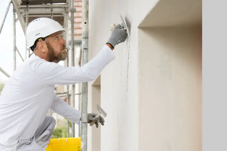 technicien d'application applicant un enduit à la taloche sur une façade