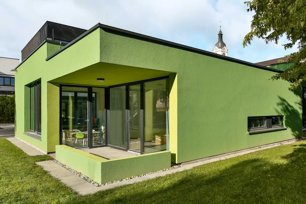 Vue extérieure d'une crèche, façade verte, isolée avec des fibres de bois Sto EWIS